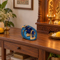 Blue and Gold Baby Krishna Figurine on Leaf Base displayed in a home setting
